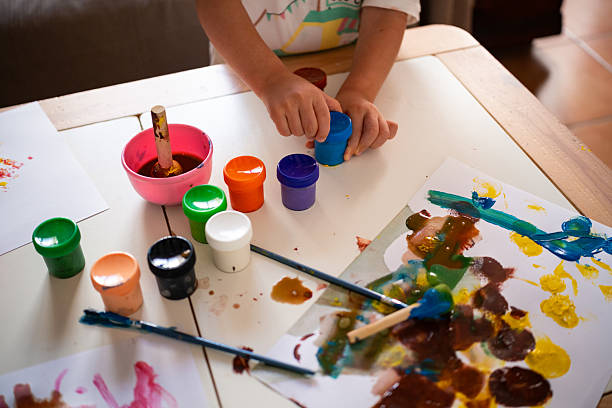 istock Child opens paint jar during painting activity at home with daylight 2229535583