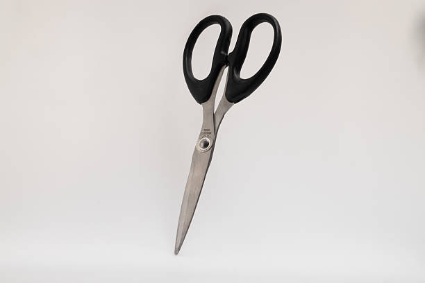 istock A pair of silver-bladed scissors with black handles stands upright on a plain white background 2229536532