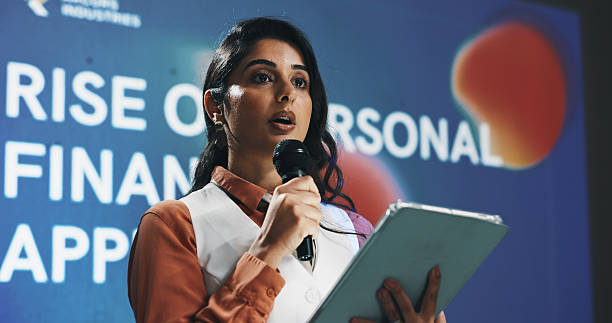 istock Presentation, speech and tablet with business woman at symposium for financial development. App, event and stage with Indian speaker in auditorium for introduction to personal finance solutions 2229538275