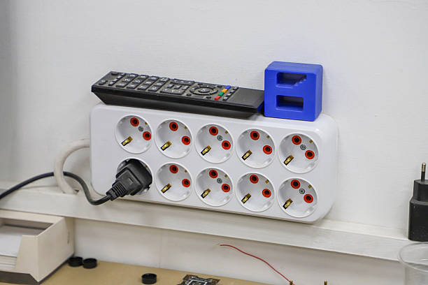 istock A white power strip with eight outlets mounted on a white wall, with a black remote control placed on top. 2229542435