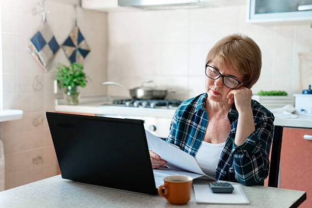 istock Stressed senior woman working from home kitchen with laptop, managing finances, paying bills. Burnout syndrome, depression. Personal budgeting, stressful retirement. Financial losses, money anxiety 2229542492