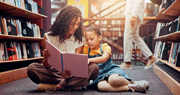 istock Kid, learning or teacher reading book for storytelling, development or growth in school. Teaching, tutor or woman with girl or child in library for literature lesson, fairy tale or education support 2229544246
