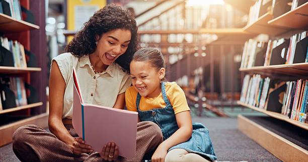 istock Child, library or teacher with book for laughing, development or help in school for humor. Teaching, tutor or woman with girl, funny joke or kid for literature lesson, fairy tale or education support 2229544282