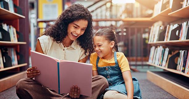 istock Happy child, story or teaching in school with book, development or learning growth in library. Teacher, smile or woman tutor with girl, education or kid for literature lesson, fairy tale or fantasy 2229544287
