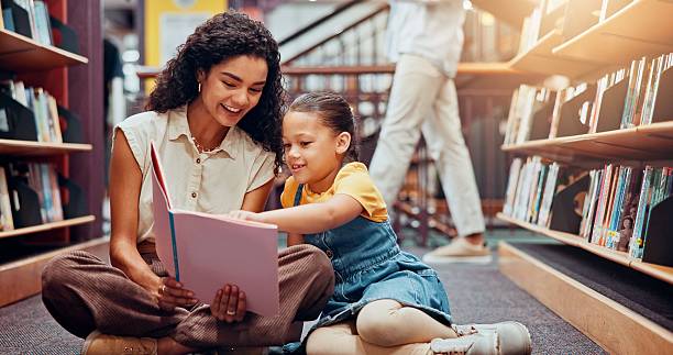 istock Kid, help or teacher reading book for learning, child development or talking in school. Teaching, smile or woman with girl or student in library for literature lesson, fairy tale or education support 2229544298