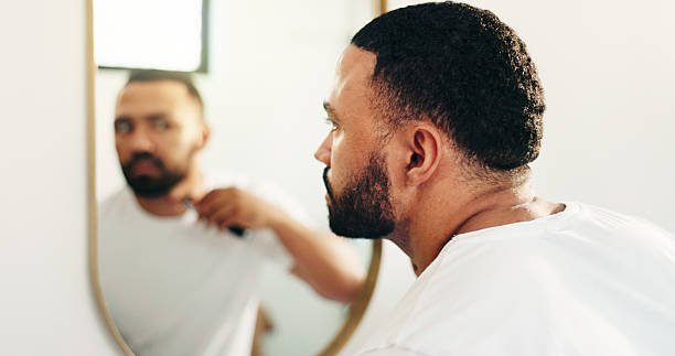 istock Man, razor or shaving beard at mirror in bathroom for grooming, clean face or self care routine. Hygiene, reflection or person with cosmetics tool in home for facial hair trim, skincare or depilation 2229545319