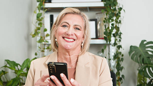 istock Smiling Senior Woman Using Smartphone in a Bright Professional Setting 2229550494