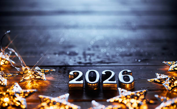 istock Shiny Silver 2026 Surrounded by Glowing Star Lights on Dark Wooden Background 2229553764