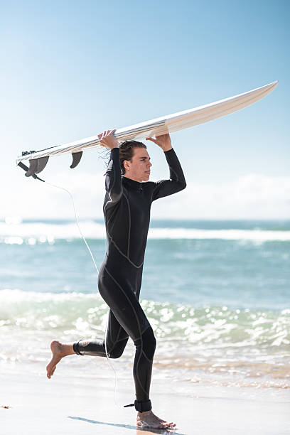 The Pacific Rim National Park in British Columbia on March 02, 2024: Young male surfer returning after a session at Pacific Rim National Park on Vancouver Island at sunset, British Columbia