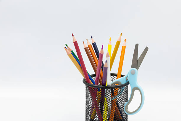 istock Colorful pencils and scissors resting in a pencil holder on white background 2229562507