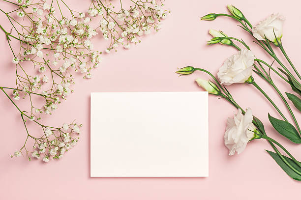 istock Delicate white eustoma and gypsophila flowers and a blank card on a pink background. Flat composition. Postcard, invitation 2229566638