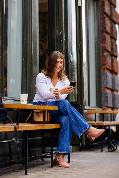 istock Happy young woman using mobile phone and enjoying coffee at cafe 2229566647