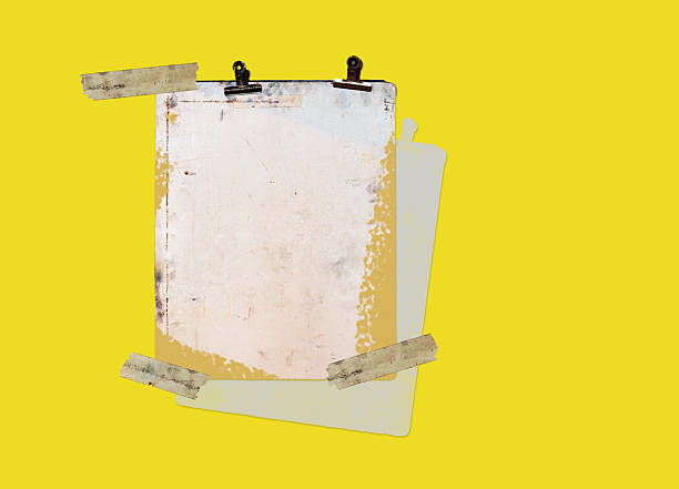 istock An old, weathered clipboard with rusted clips is tilted diagonally on a yellow background, accentuated by an expressive  brushstroke 2229566659
