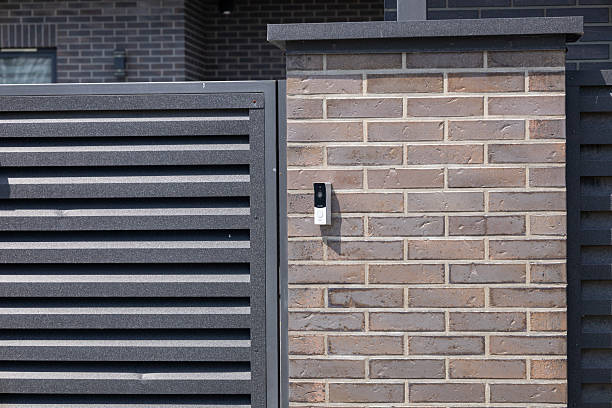 istock A contemporary intercom system is mounted on a textured brick wall next to a slatted gate in a modern residential neighborhood 2229568917