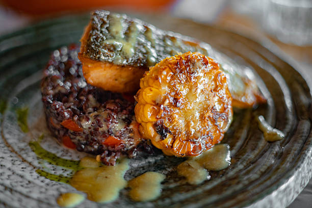 Salmon fillet served alongside corn and black rice, gourmet seafood dish, rich in protein, healthy and satisfying