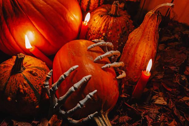 istock Autumn Halloween themed design layout with spooky decor.place for text.  Pumpkins set, bone hands and red candles in the dark. 2229572346