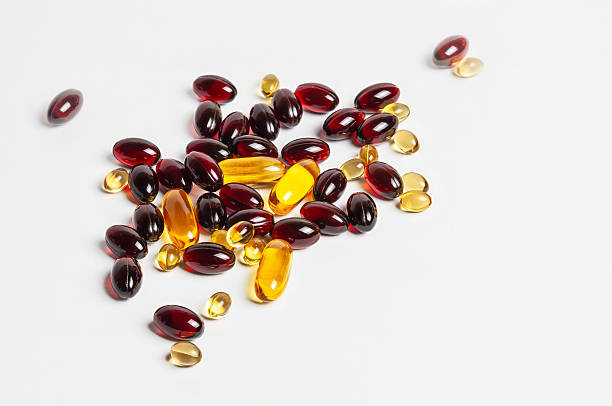 istock A close-up of various red and yellow capsules scattered on a white surface. 2229573068