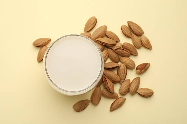 istock Fresh nut milk in glass and almonds on beige table, top view 2229576782