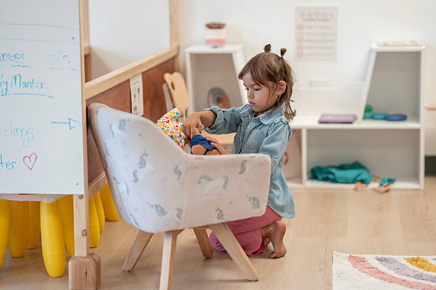 A child plays with toys in a well-lit classroom. The setting emphasizes creativity, imagination, and learning, showcasing organized furniture, interactive areas, and a nurturing educational atmosphere for young minds.