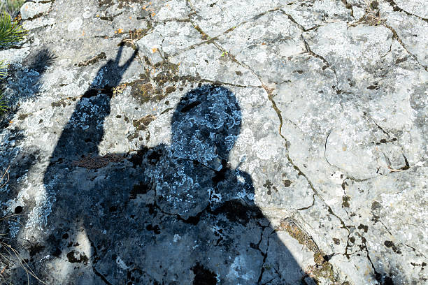 istock a shadow on a stone, a man raises two fingers up 2229577157