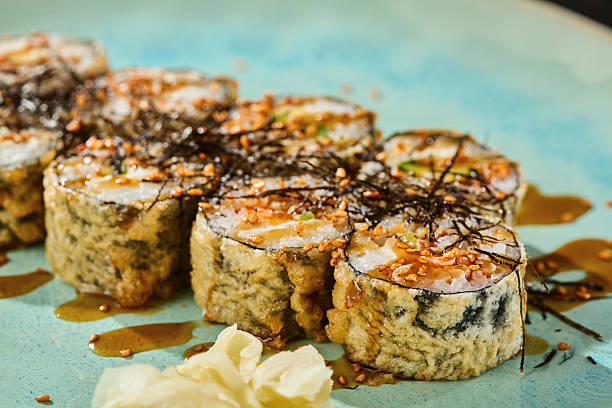 istock Tempura salmon roll, moody lighting, overhead composition with spicy sauce on blue ceramic plate 2229578472