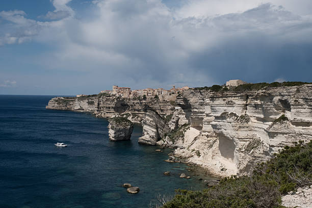 Dramatic view of Bonifacio, a seaside town in southern Corsica, with cliffs, fortifications and moody clouds. A scenic Mediterranean destination rich in history and natural beauty.