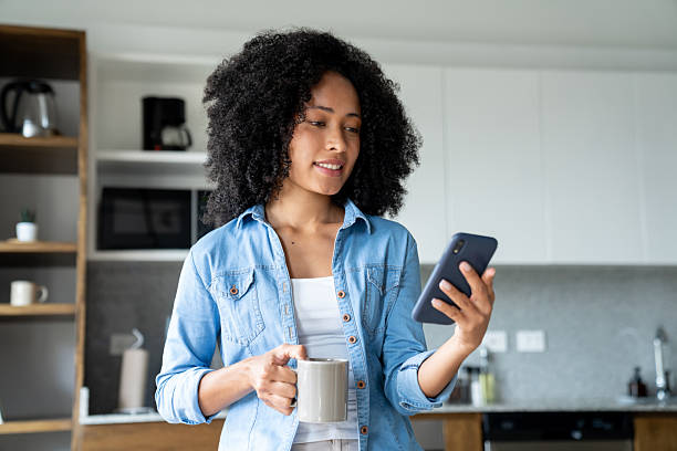 istock Woman at home texting on her phone while drinking a cup of coffee 2229579781