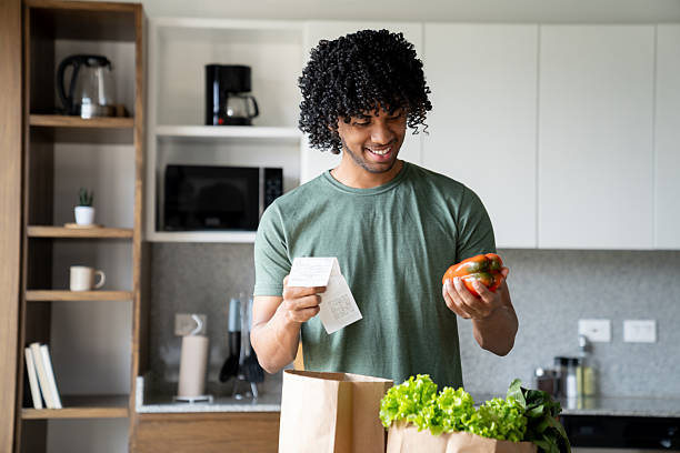 istock Man at home unpacking the groceries while checking the receipt 2229579790