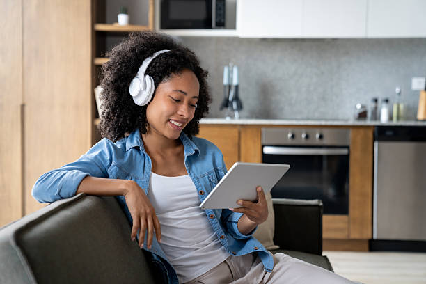 istock Woman at home watching videos on her tablet while using headphones 2229579833