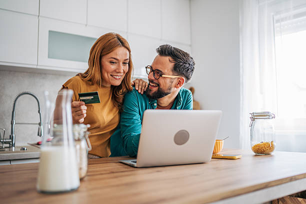 istock Happy couple making online payment using credit card in kitchen 2229580717
