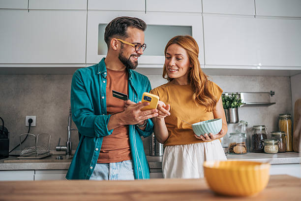 istock Couple using smartphone and credit card for online shopping in kitchen 2229581442