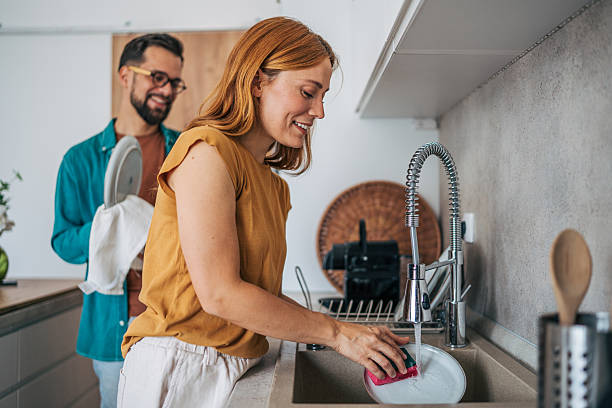 istock Young couple washing dishes together in modern kitchen 2229581627