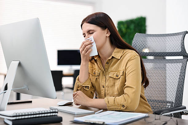 istock Sick woman with runny nose at table in office 2229581804