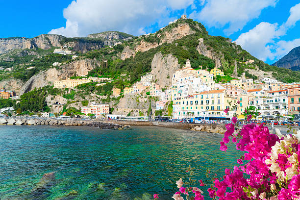 Portrait of smiling female tourist with long hair exploring Amalfi Coast and walking the authentic streets with colourful houses by the sea