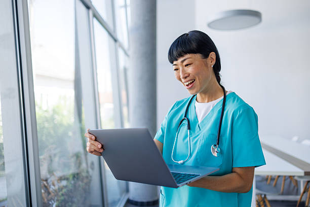 istock Happy doctor using laptop in modern hospital setting is smiling 2229583364
