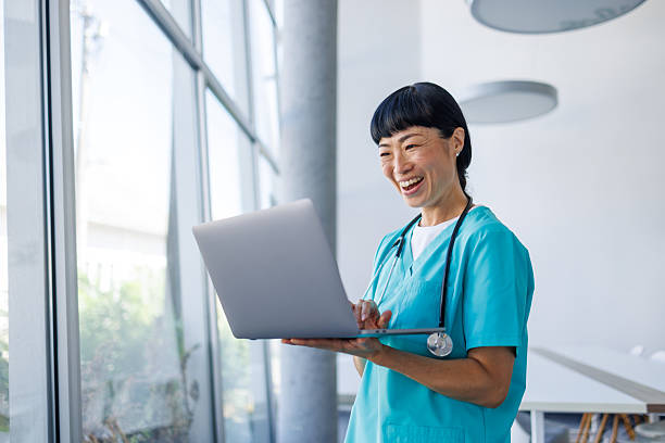 istock Smiling doctor using laptop in modern hospital setting 2229583367