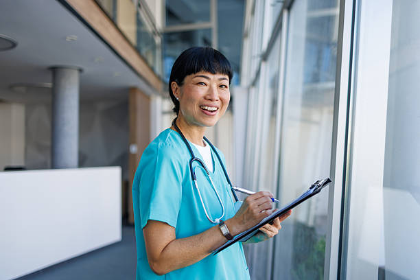 istock Smiling doctor writing on clipboard in hospital corridor 2229583390