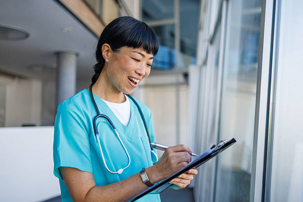 istock Smiling nurse taking notes on clipboard in hospital 2229583402