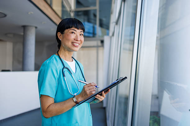 istock Smiling nurse taking notes on clipboard in hospital corridor 2229583418