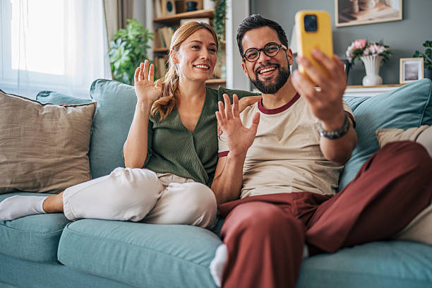 istock Happy couple video calling with family using smartphone at home 2229583421