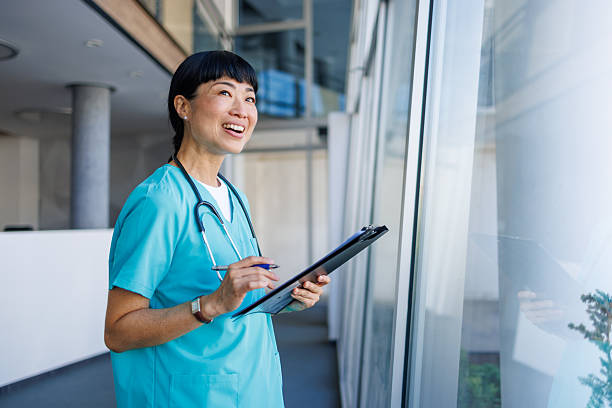 istock Smiling nurse looking out window in modern hospital 2229583518