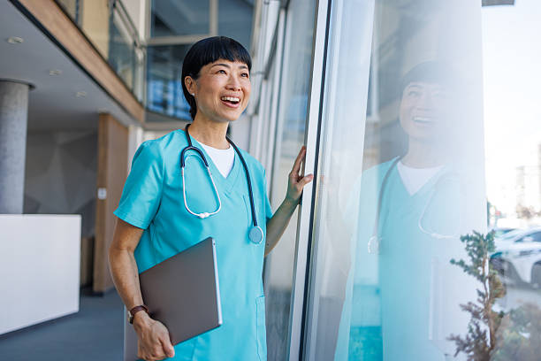 Smiling doctor looking out window in modern hospital
