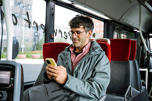 istock Commuter going to workby public bus and wearing backpack, man is using smart phone while on the move 2229585845