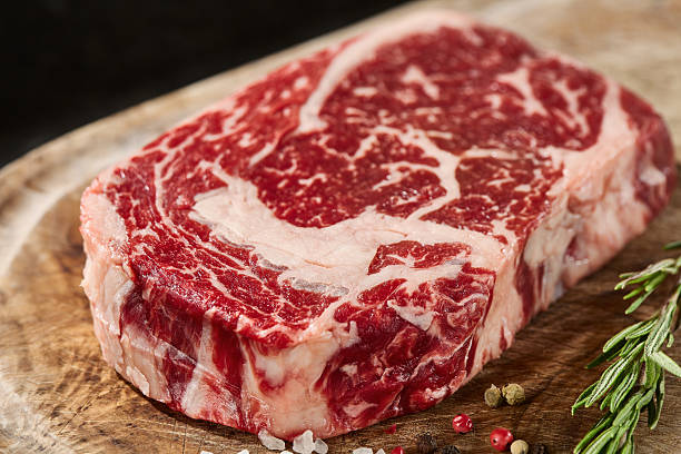 istock Ribeye steak on wooden board, moody lighting, closeup composition with rustic surface 2229589486