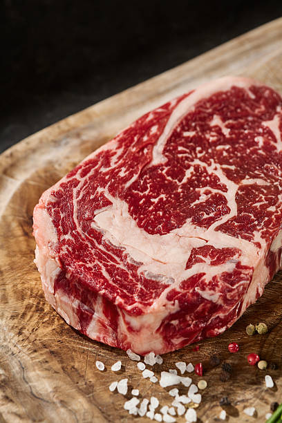 istock Ribeye steak with marbling, rustic lighting, overhead composition on a wooden board 2229589550