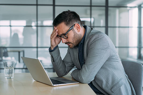 istock Stressed businessman having headache while working on laptop in the office. 2229599530