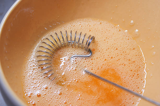 istock Whisk mixing eggs in a bowl with bubbling orange mixture 2229599830