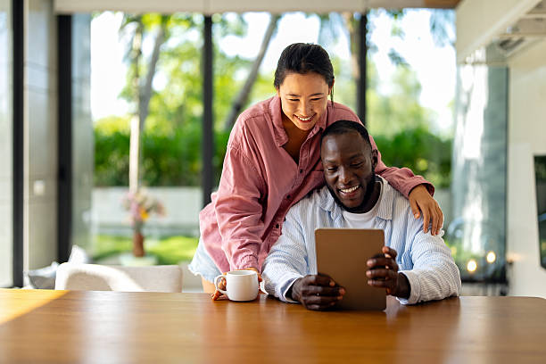 istock Young happy multiethnic couple having fun while using tablet at home. Happy couple discussing future 2229601900