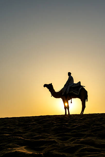 istock Indian Man Riding Camel During Sunrise at Thar Desert in Rajasthan 2229602897