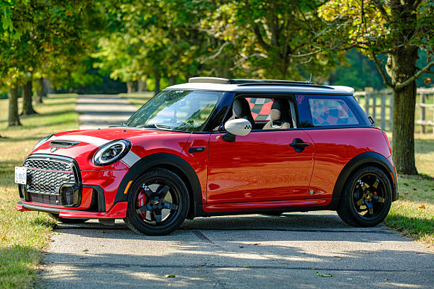 Uxbridge, Ontario, Canada- August 10, 2025. Chili red colour MINI COOPER at the rural location in Southern Ontario, Canada.  This is the third generation model F56 JCW, since BMW took over iconic brand of MINI. MINI featured in the photo is John Cooper Works model, the most powerful 2 door version. For the first time, this compact car features engine build and designed by BMW, and packs even more power and torque than previous models since 2002 to present. Original design clues and themes are still present on this brand new model. Mini has been around since 1959 and has been owned and issued by various car manufacturers.